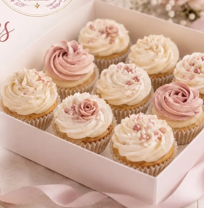Boîte de cupcakes roses et blancs décorés de fleurs en crème, de perles et de petites roses