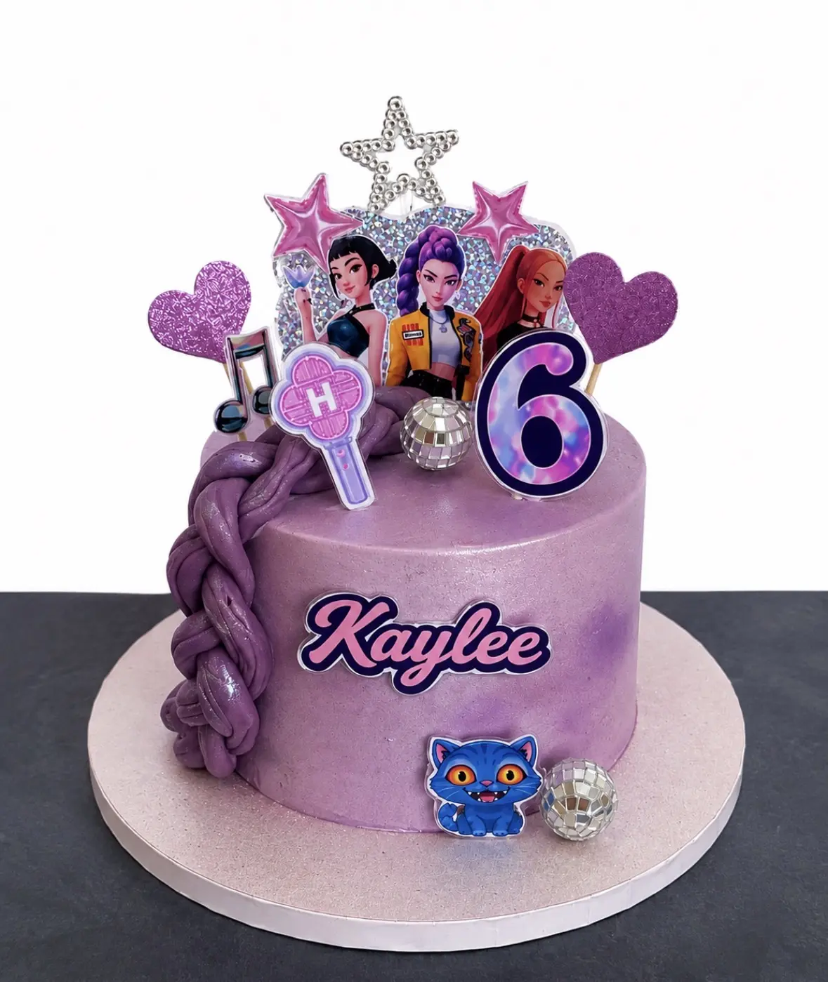 Gâteau violet pour les six ans de Kaylee, décoré de trois héroïnes pop, d’étoiles, de cœurs, de notes de musique et de boules disco