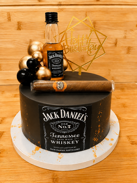 Layer cake noir sur le thème Jack Daniel’s décoré d’une étiquette Old No.7, d’une mini-bouteille de whisky, d’un cigare et de sphères noires et dorées