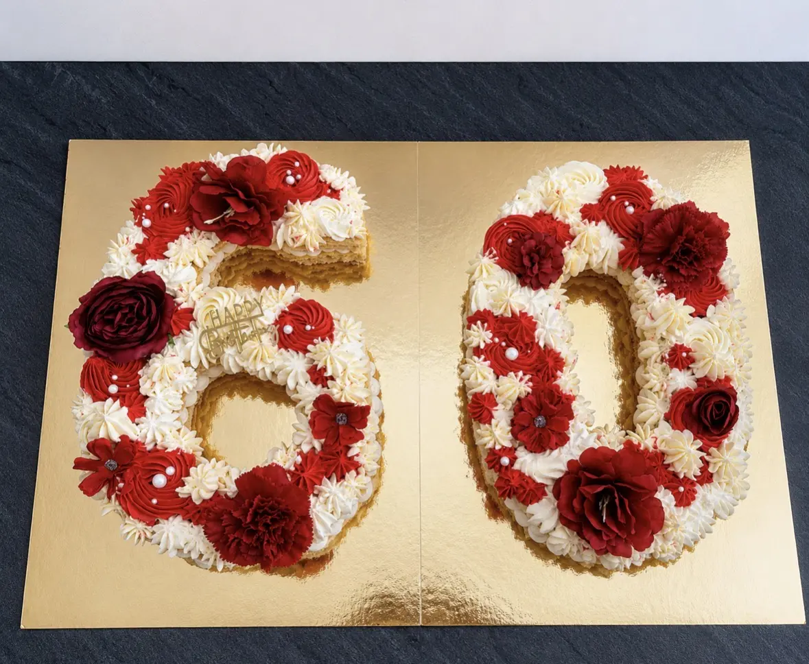 Number cake en forme de nombre 60, décoré de crème rouge et ivoire, de fleurs rouges et de perles blanches