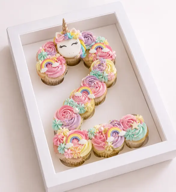 Number cake en forme de chiffre 2 composé de cupcakes pastel décorés de licornes, d’arcs-en-ciel et de nuages