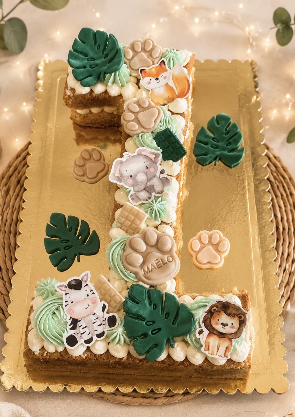 Number cake en forme de chiffre 1 pour Maëlo, décoré d’animaux de la jungle, de feuillages tropicaux et de biscuits empreintes